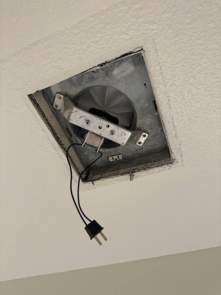 Old bathroom exhaust fan removed from the ceiling during replacement
