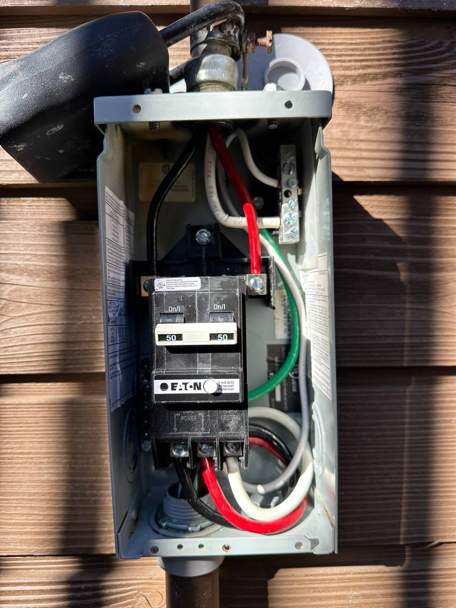 Outdoor hot tub disconnect box with the cover off, showing a 50 amp GFCI breaker and its wiring